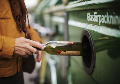 Hand putting bottle into recycling bin