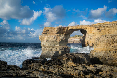 Rock formation on beach against sky