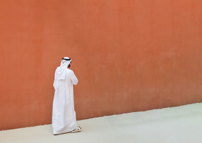 Rear view of woman standing against white wall