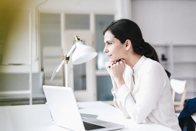 Businesswoman with laptop at table thinking