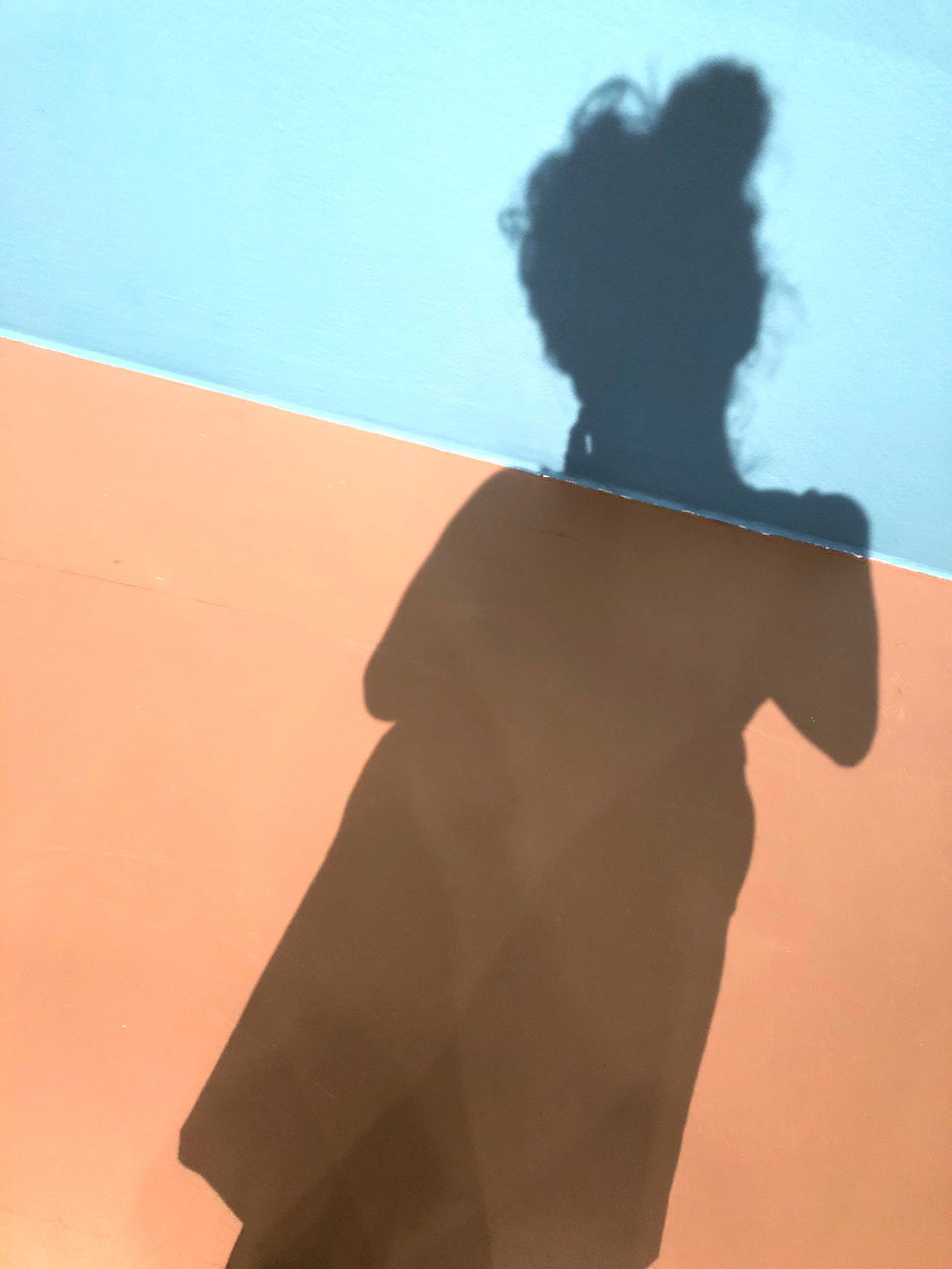 WOMAN STANDING BY SWIMMING POOL AGAINST WALL