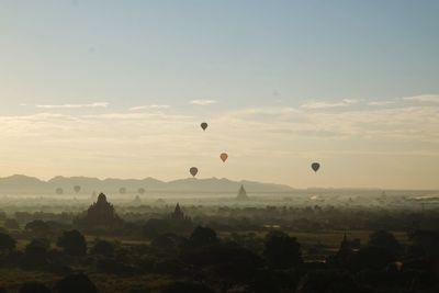 Hot air balloons flying over landscape against sky