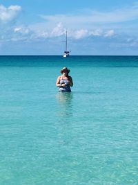 Woman standing in sea against sky