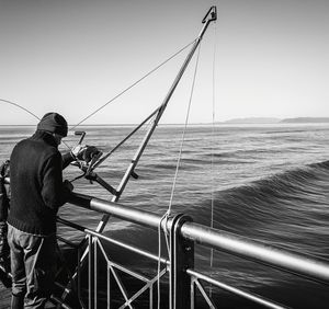 Man fishing in sea against clear sky
