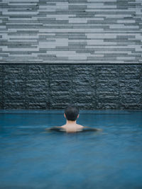 Rear view of man swimming in pool