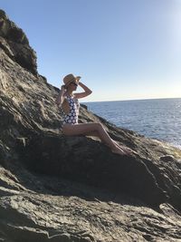 Full length of man on rock in sea against sky