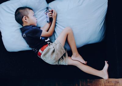 High angle view of boy using smart phone on sofa at home