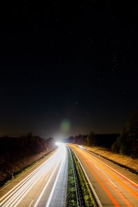 Light trails on road against sky at night