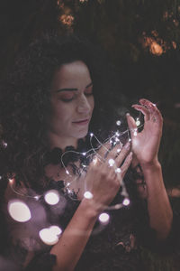 Close-up of beautiful woman holding illuminated lights