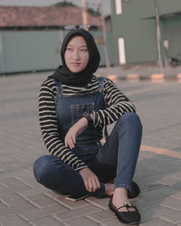 Teenage girl sitting on footpath