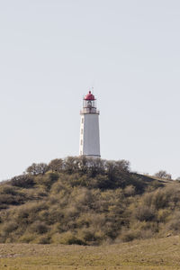 Low angle view of lighthouse amidst buildings against clear sky