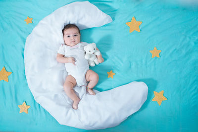 Beautiful latin baby girl, two months old, lying on a white sheet in the shape of a moon