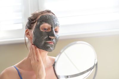 Close-up of woman applying mask at home