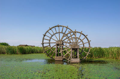 Ferris wheel by lake against clear sky