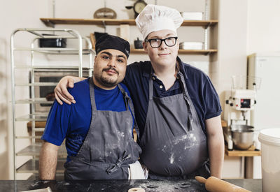 Portrait of bakers standing by table in kitchen