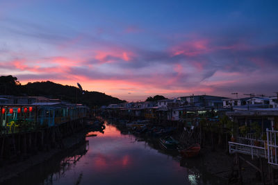 Canal amidst buildings against sky at sunset