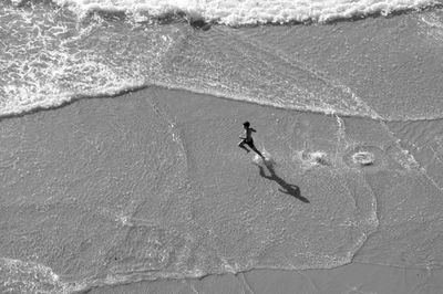 High angle view of boy running on wet shore