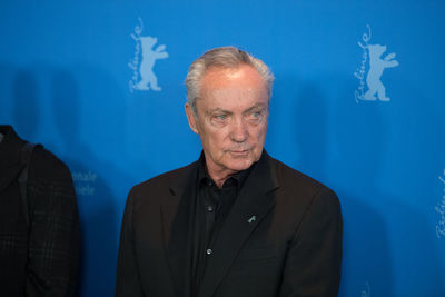 Portrait of man standing against blue wall