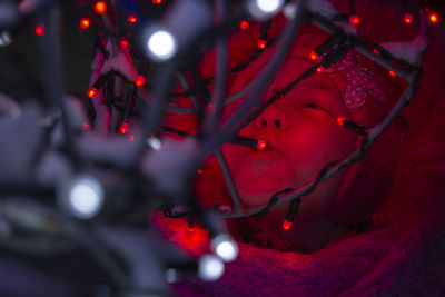 Close-up of baby girl against illuminated red lights