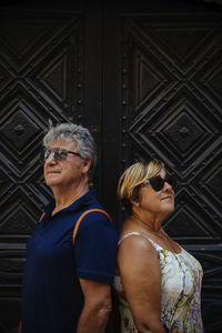 Senior couple wearing sunglasses while standing against closed doors