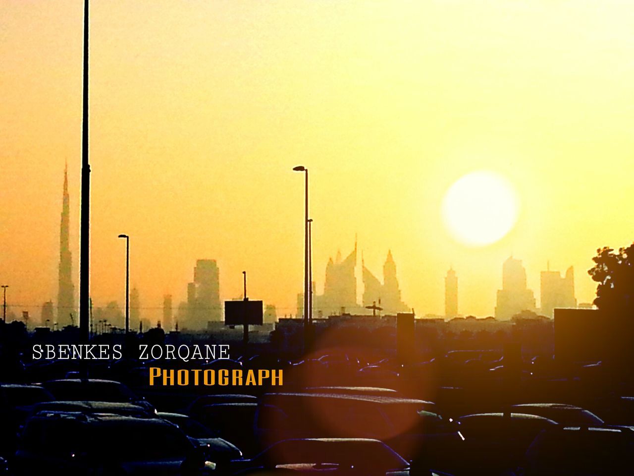 transportation, land vehicle, mode of transport, sunset, car, city, road, street, street light, sun, traffic, built structure, architecture, orange color, building exterior, parking lot, sky, on the move, clear sky, travel