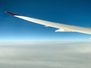 Airplane wing against clear blue sky