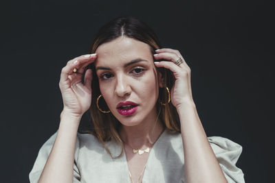 Portrait of young woman holding camera against black background