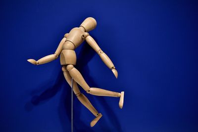 High angle view of figurine on wood against blue background