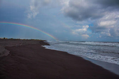 Scenic view of sea against rainbow in sky