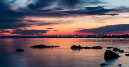 Scenic view of sea against dramatic sky during sunset