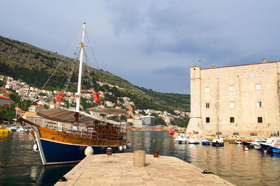 Boats moored at harbor by sea against sky