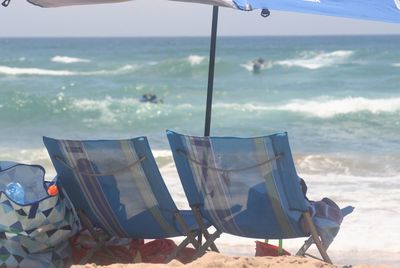 Close-up of deck chairs on beach against sky