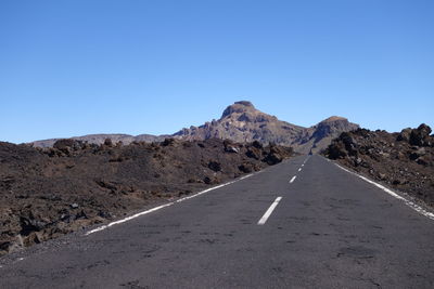 Road amidst mountains against clear blue sky