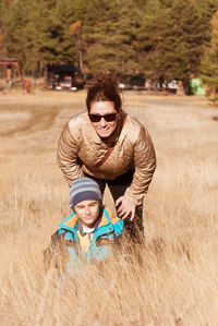 Portrait of smiling woman with son on grassy field