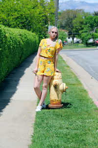 Portrait of woman standing by fire hydrant against trees
