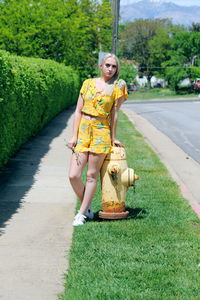 Full length of smiling woman on grass against trees