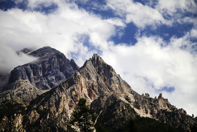 Low angle view of dolomites against cloudy sky