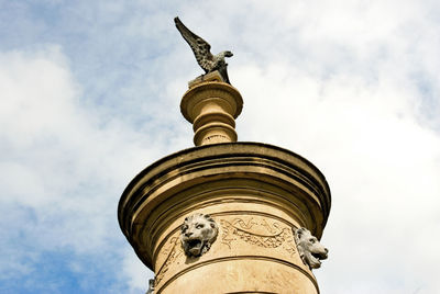 Low angle view of statue on column against cloudy sky