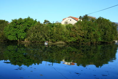 Reflection of trees in lake against clear sky
