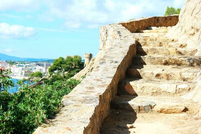 Low angle view of stonewall and staircase against sky