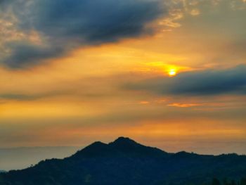 Scenic view of silhouette mountains against orange sky