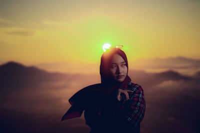 Portrait of beautiful young woman standing against sky during sunset