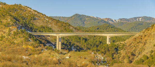 Arch bridge over mountains against clear sky