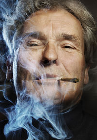 Close-up portrait of senior man smoking cigarette