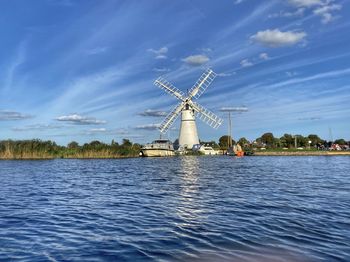 Cranes by river against sky