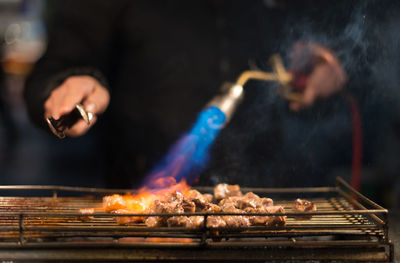 Close-up of man cooking on barbecue grill