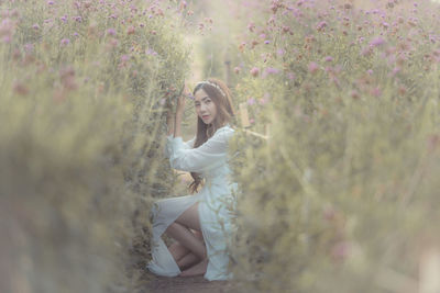 Young woman with arms raised against trees