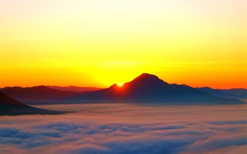 Scenic view of mountains against dramatic sky during sunset