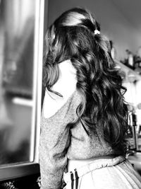 Rear view of woman looking at mirror standing at home