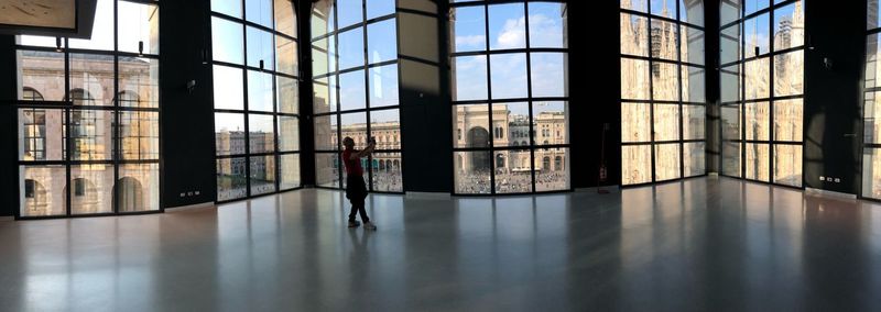 Panoramic view of man standing by window in building